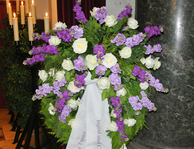 Bestattung in Frankfurt mit grünem Kranz und lila Blumen